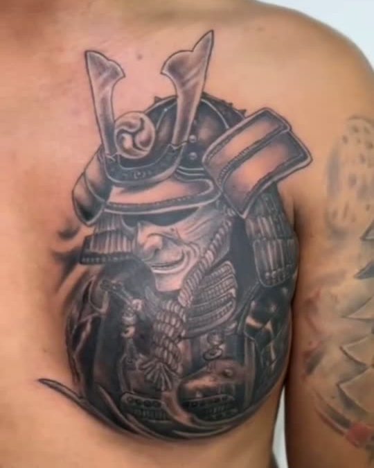 Black and grey sacred heart tattoo with rays and lettering, freshly tattooed on a chest