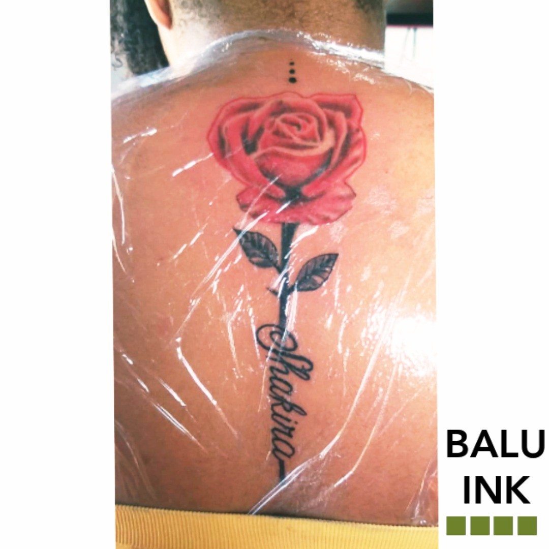 Red rose tattoo with green stem and script lettering underneath, freshly wrapped