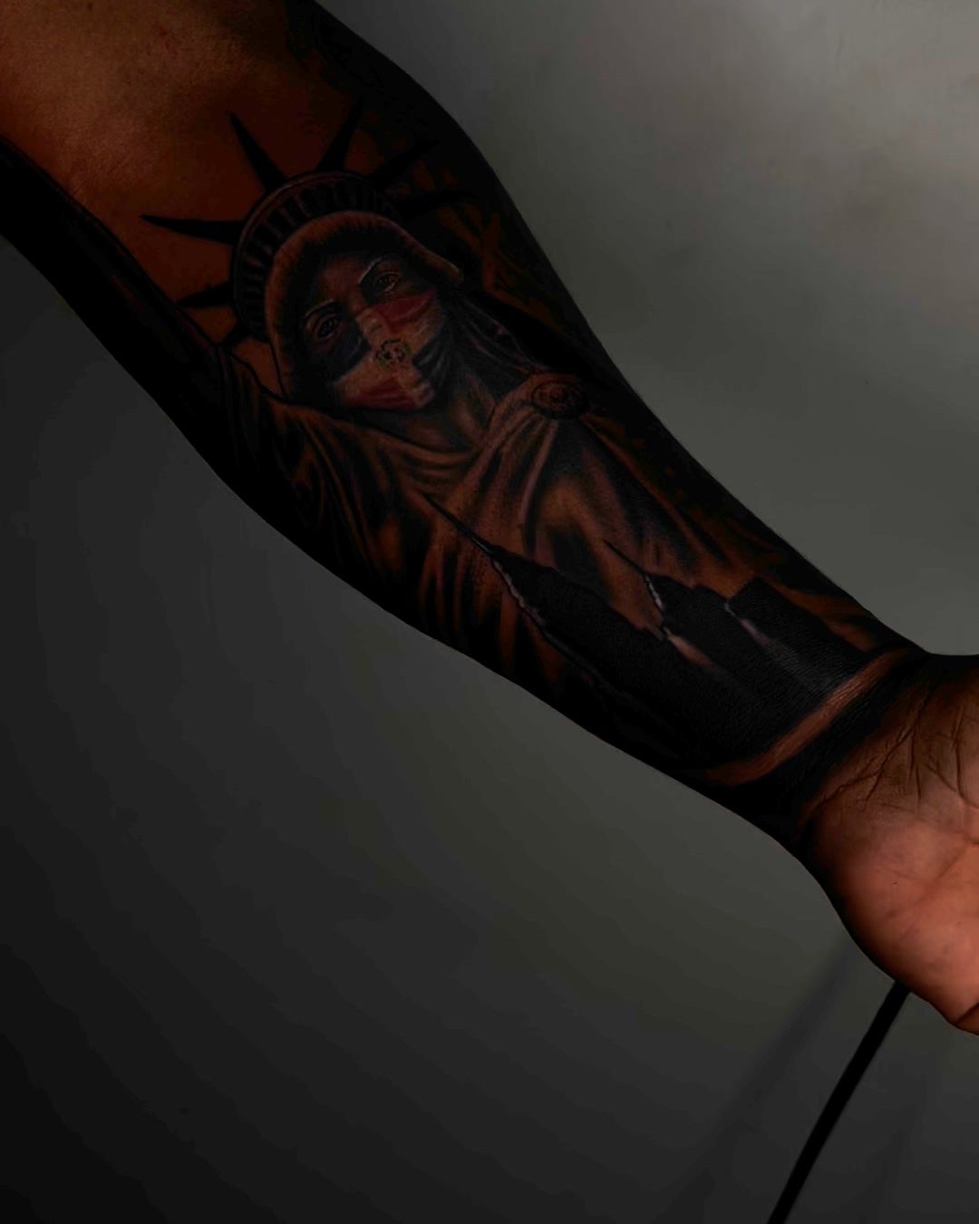 Cover-up tattoo on a forearm, new dark work shaded over an older tattoo