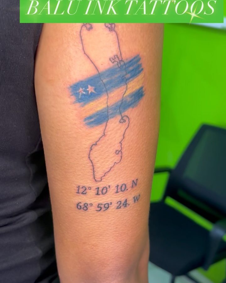 Curaçao tribute tattoo: island outline, the Curaçao flag and the island's coordinates on a forearm