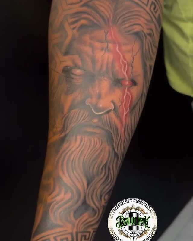 Black and grey Zeus bust tattoo, fresh on a forearm with red skin around it