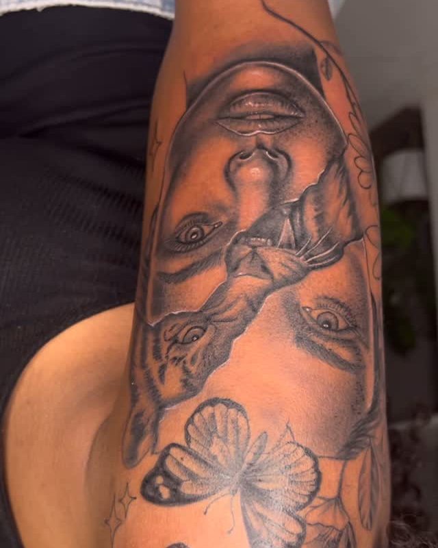 Floral tattoo with a ribbon, lilies in pink and purple tones on an arm