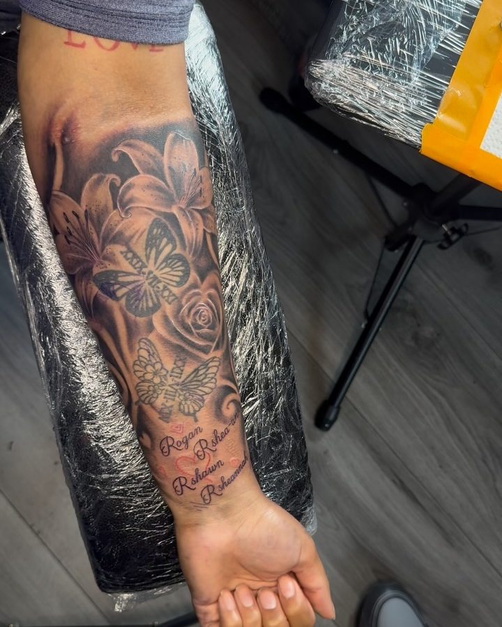 Floral black and grey sleeve mid-session, wrapped in cling film on a chair