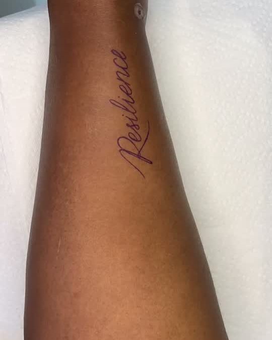 Healed fine script tattoo on a forearm